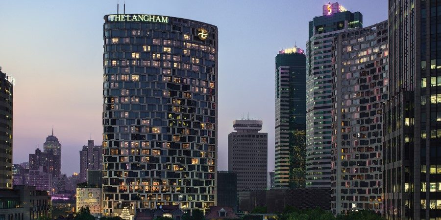 A modern hotel with sleek architecture, set against the vibrant skyline of Shanghai.